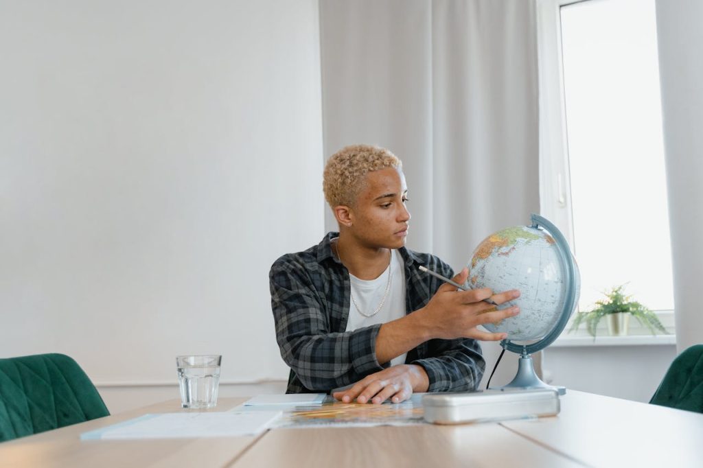 Young man studying with a globe at home, focused on distance learning indoors.