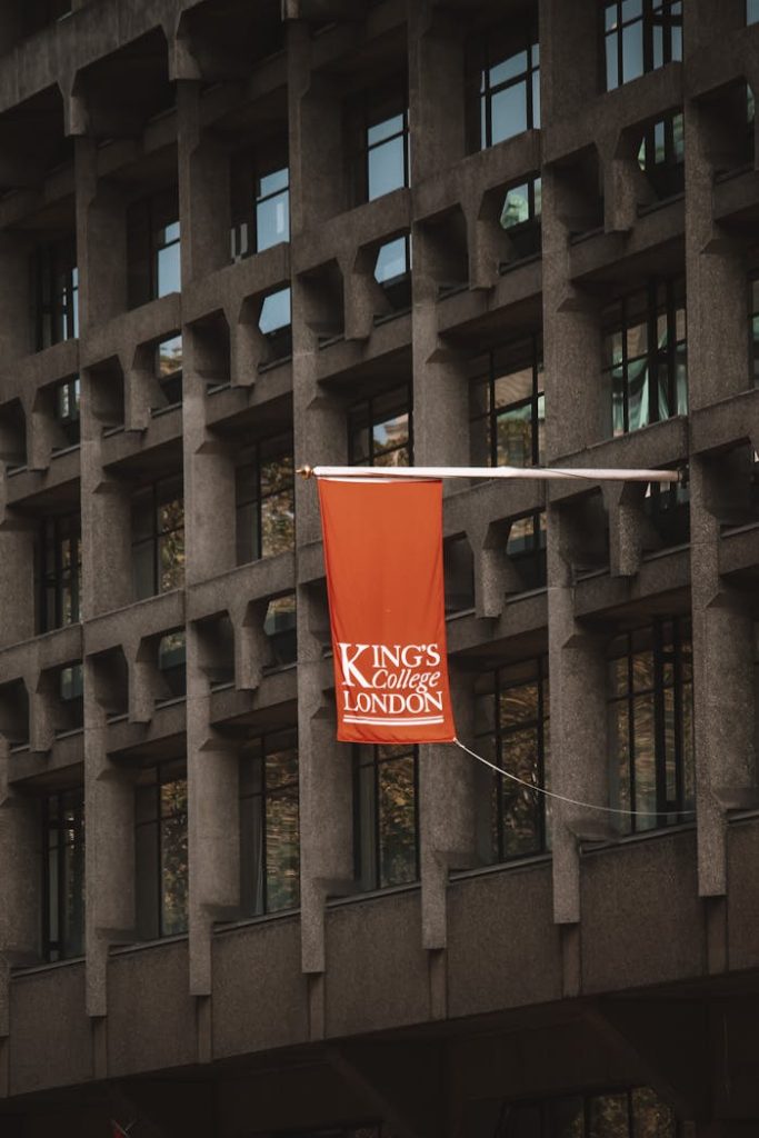 Close-up of Kings College London flag on a modern architectural building facade.