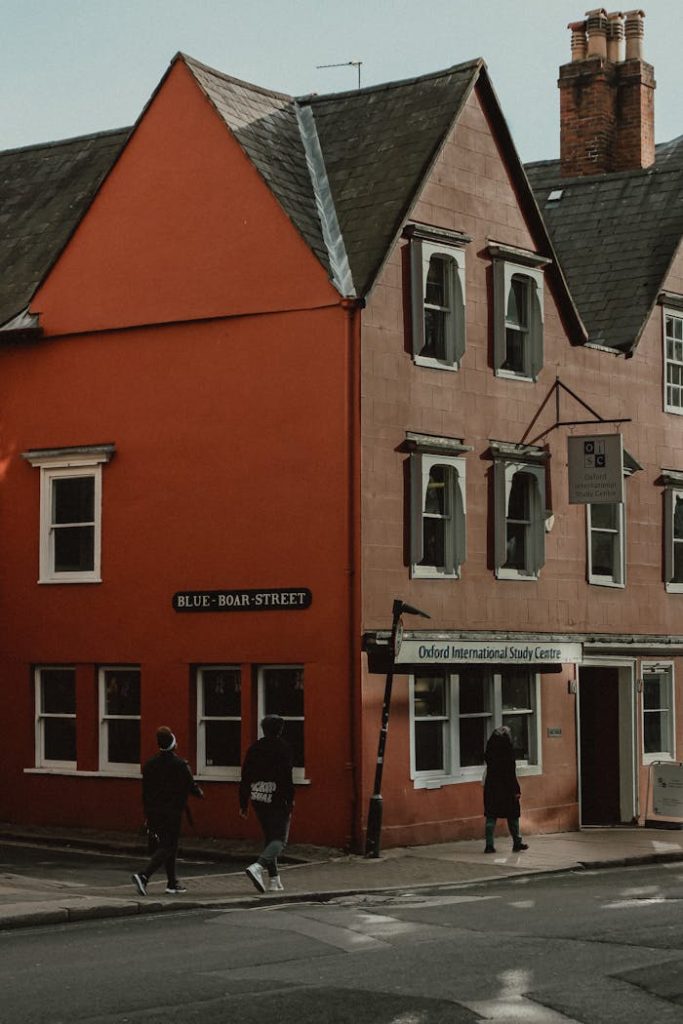Urban scene of people walking by a red building on Blue Boar Street, Oxford, UK.
