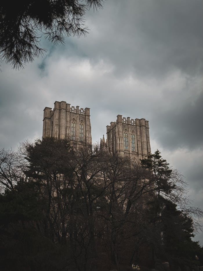 Gothic architecture of Kyung Hee University towers against a moody sky in Seoul, South Korea.